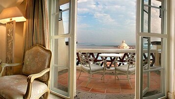 Una puerta abierta que da a una terraza con mesa y sillas, con vistas a un paisaje.