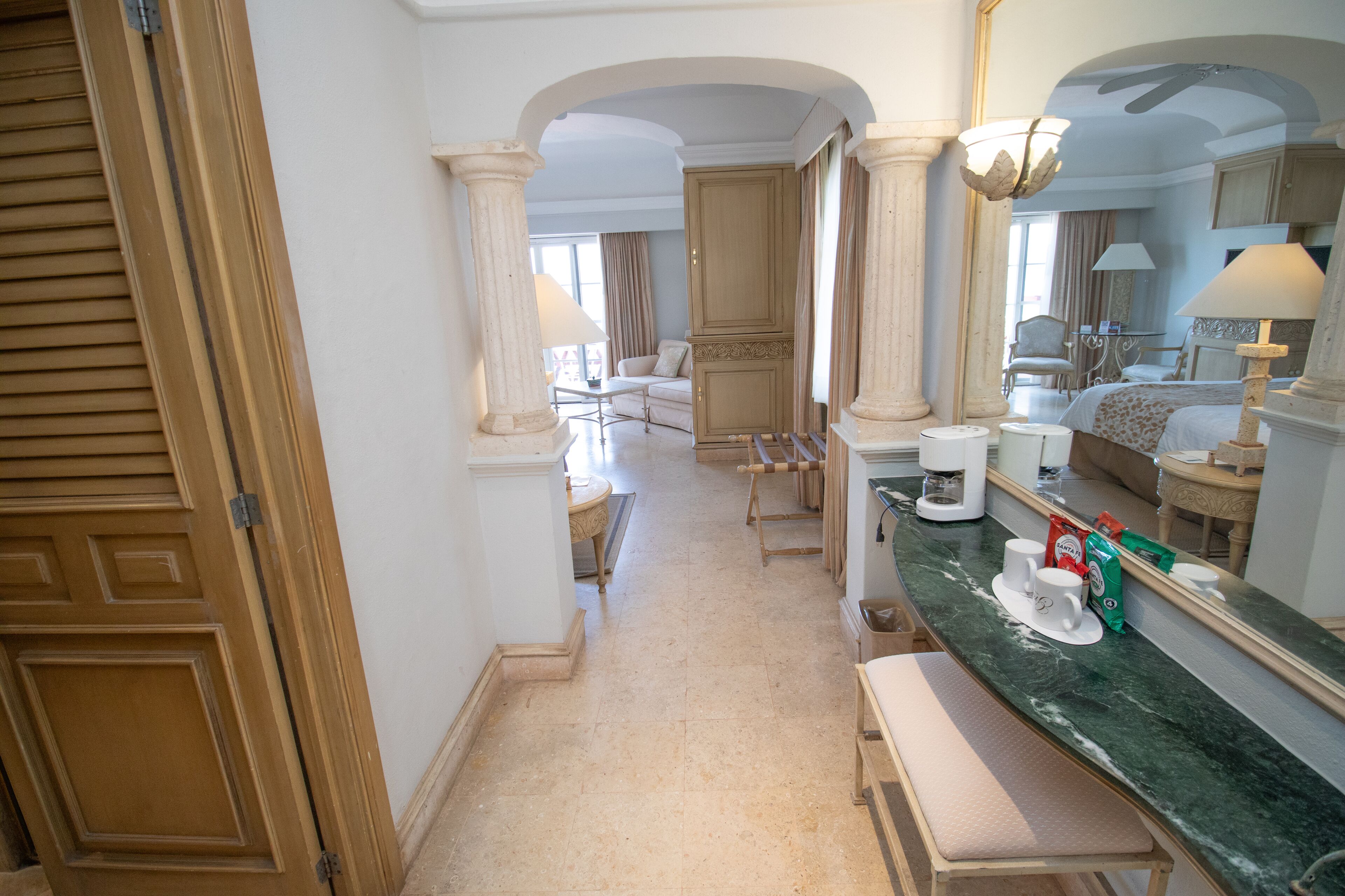 A hotel hallway with a marble counter, a coffee machine, and a seating area with a chair and a table.