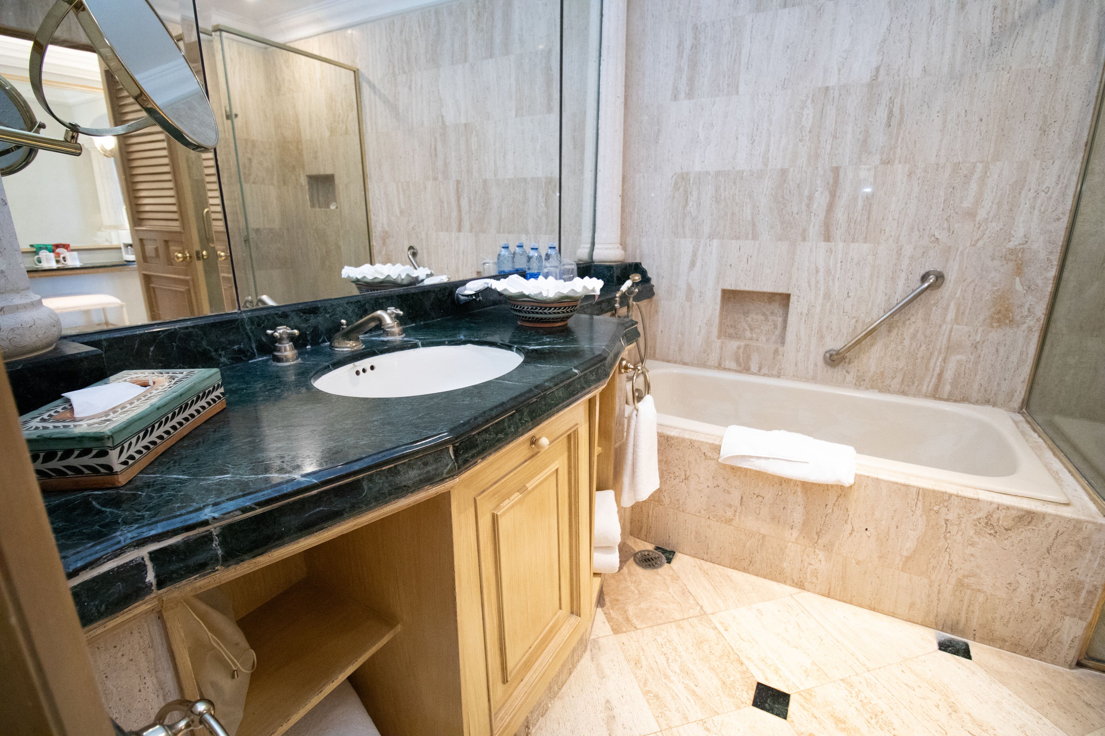 Une salle de bain avec un lavabo en marbre, une baignoire et une coiffeuse avec un miroir.