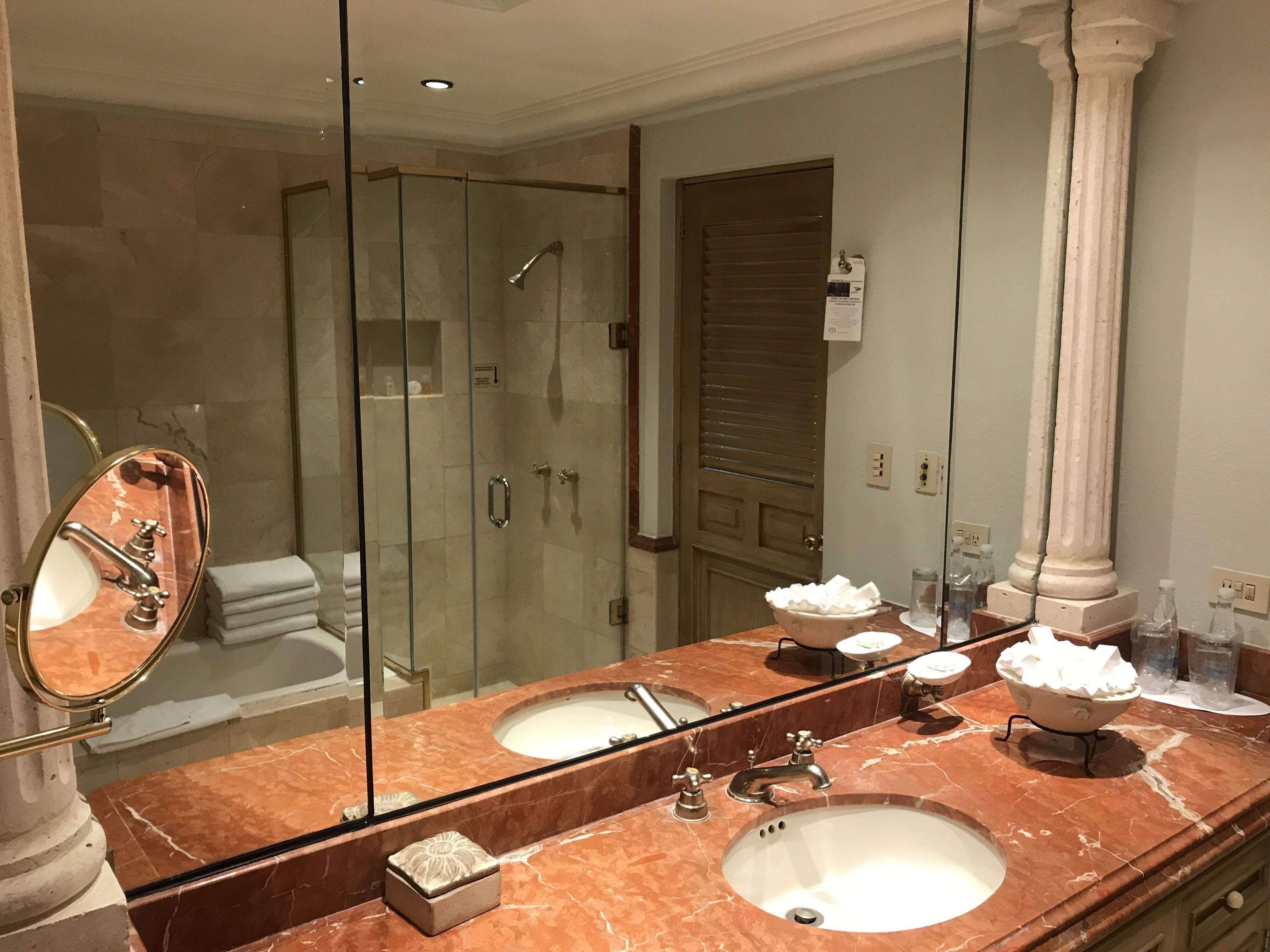 A bathroom with a large mirror, two sinks, a shower, and a bathtub.