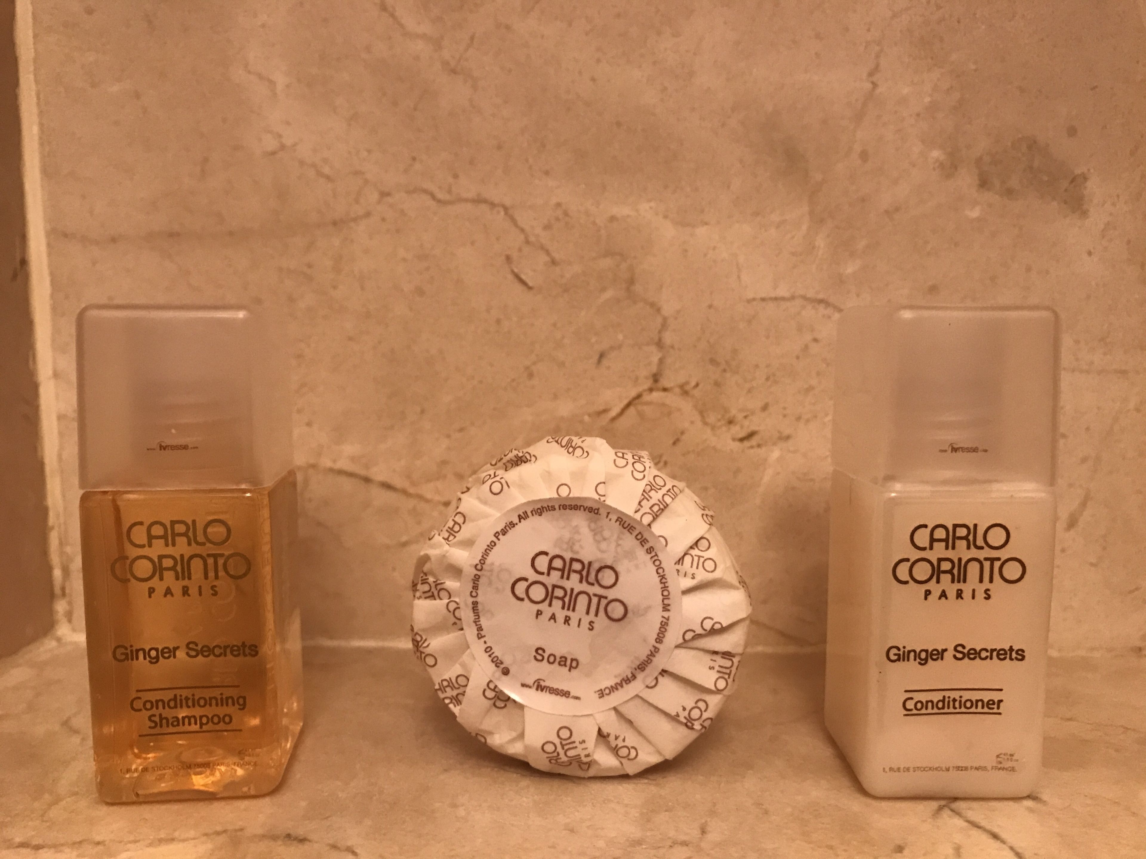 Drie flessen Carlo Coriato Paris Ginger Secrets Conditioner Shampoo en Zeep op een marmeren oppervlak.