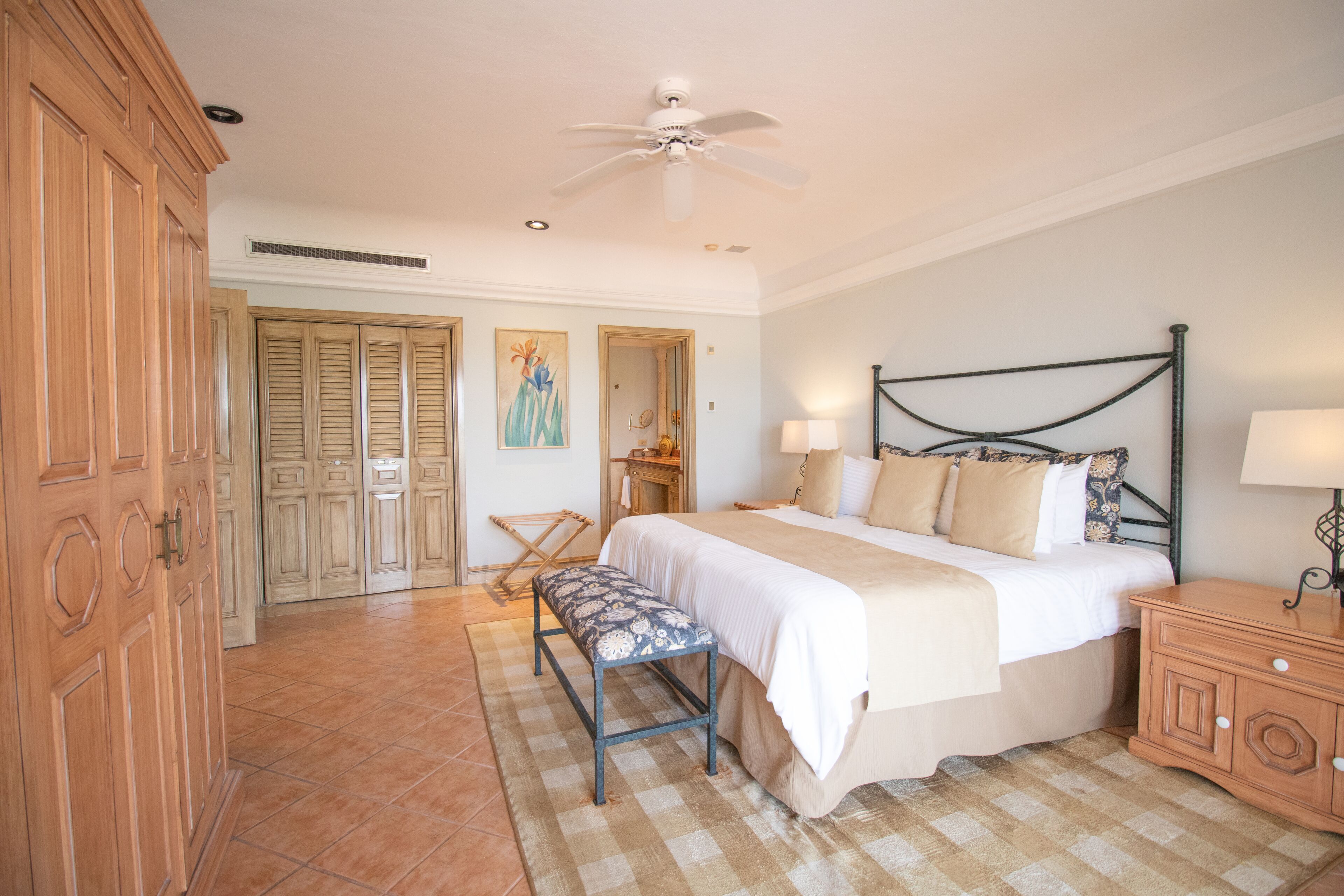 Ein Schlafzimmer mit Bett, Nachttischen, einer Bank und einem Deckenventilator.