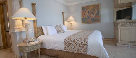 A hotel room with a large bed, two bedside lamps, a small table with a telephone, and a painting on the wall.