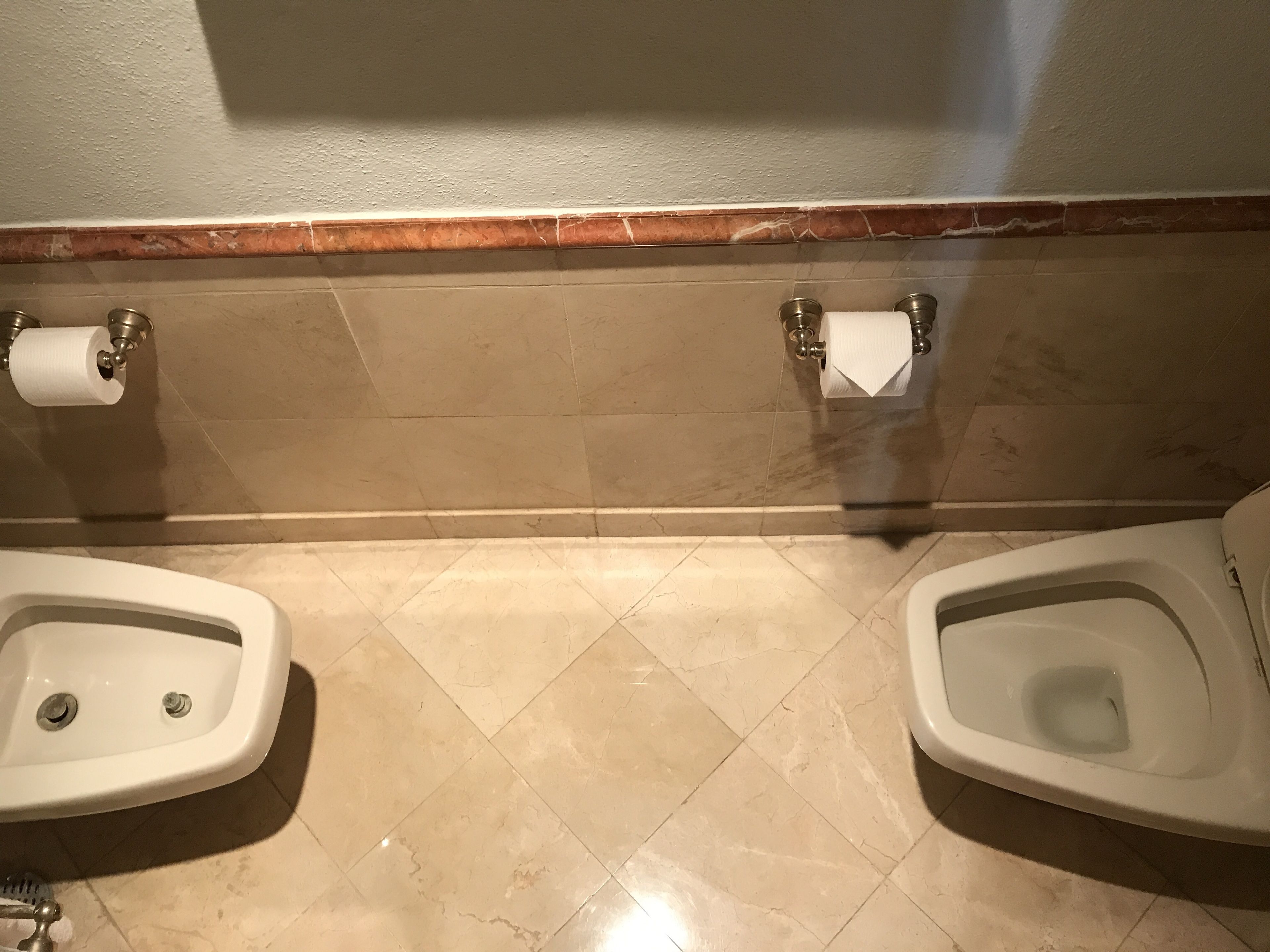 A restroom with two urinals, a toilet, and two paper towel dispensers.