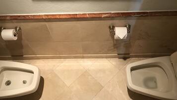 Des toilettes comprenant deux urinoirs, des toilettes classiques et deux distributeurs d’essuie-mains en papier.