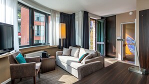 Una habitación de hotel moderna con sofá, sillón y televisor de pantalla plana.