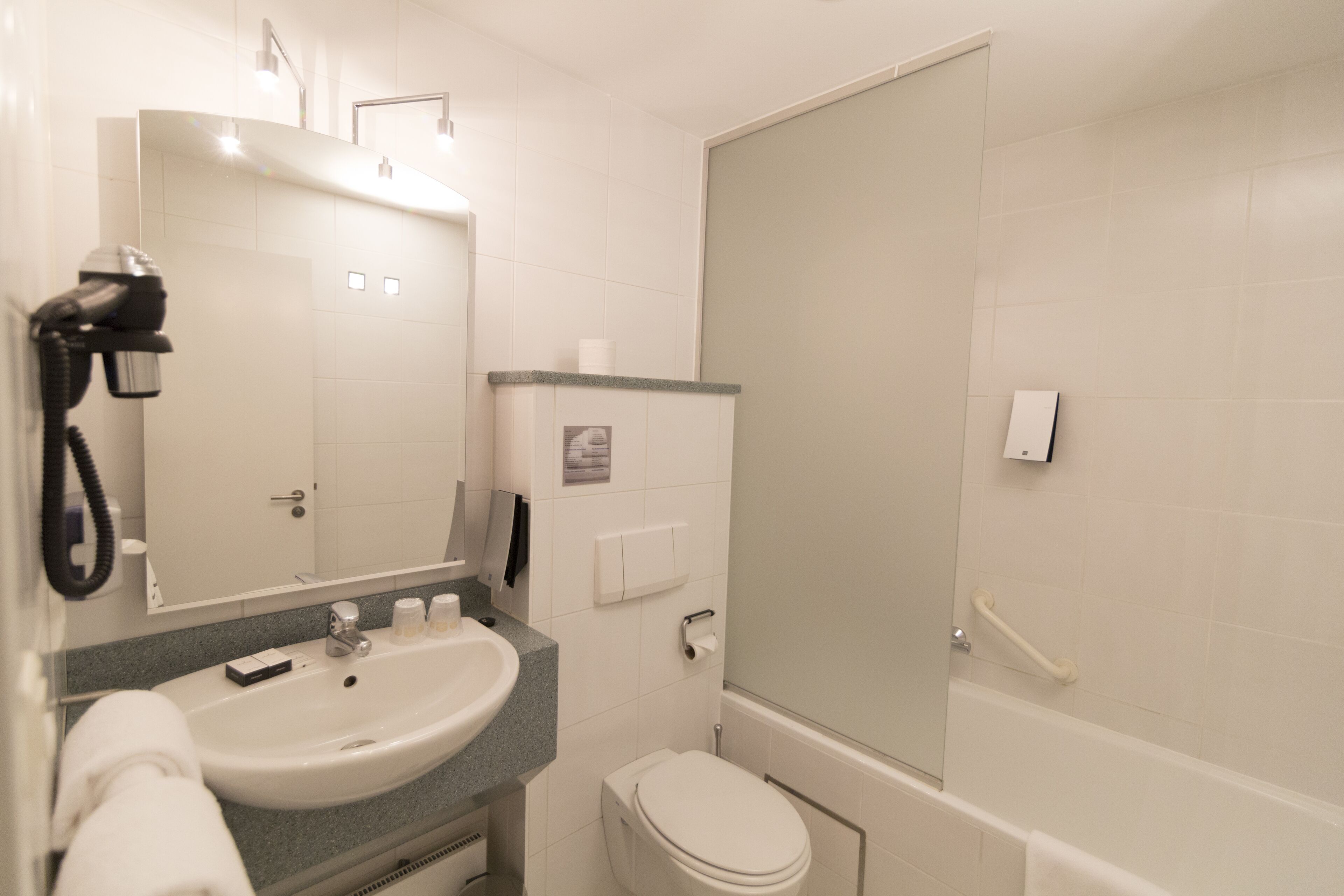 Ein Badezimmer mit Waschbecken, Spiegel, Toilette und Dusche.