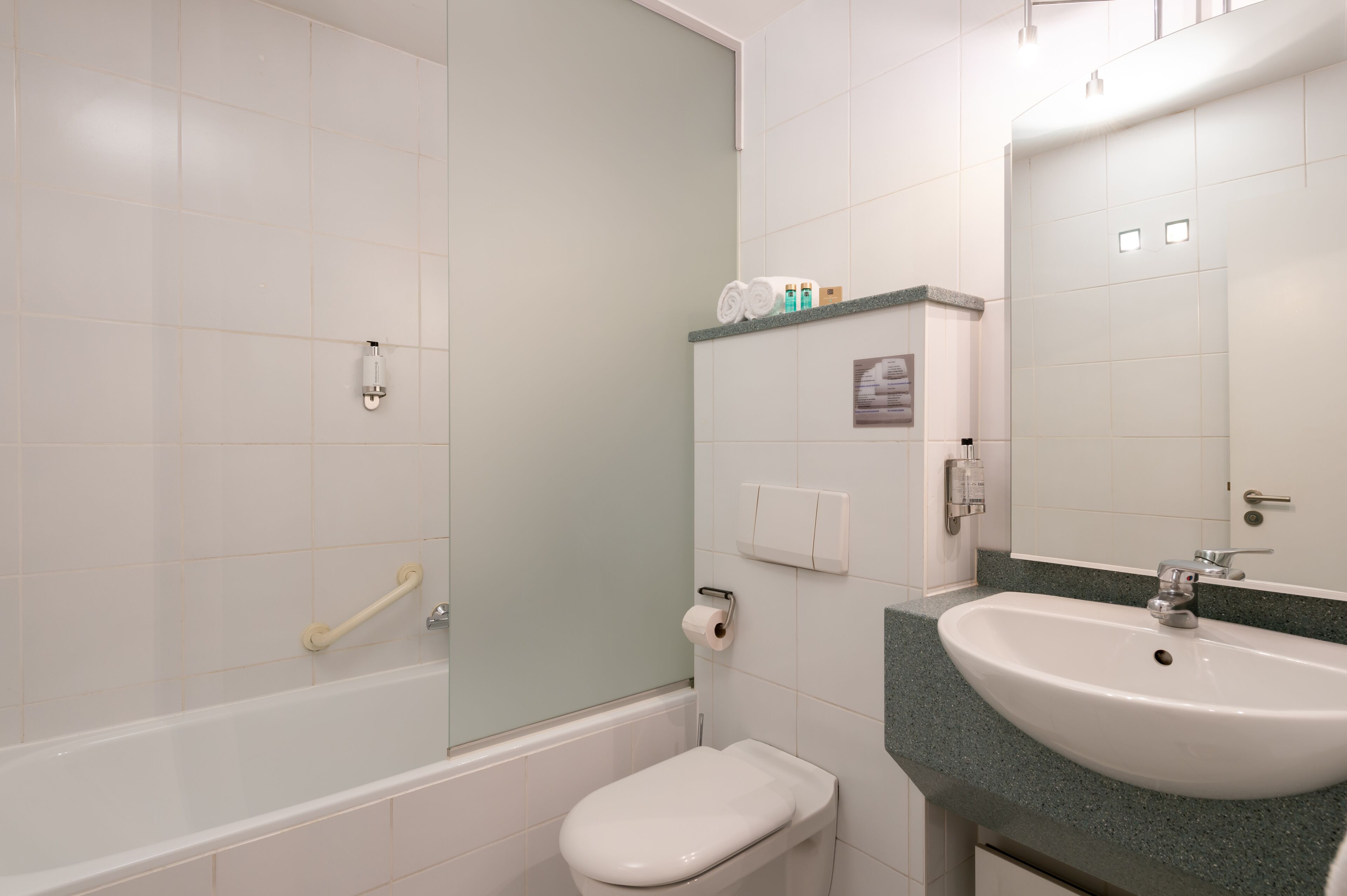 Un baño con bañera, inodoro, lavabo y espejo.