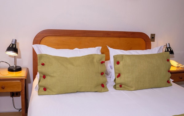 A bed with two green pillows with red buttons, a wooden headboard, and two bedside lamps. - Hotel Canciller - Ex Hotel Presidente (Santiago)