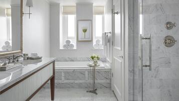 A modern bathroom with a marble sink, a bathtub, and a glass-enclosed shower.