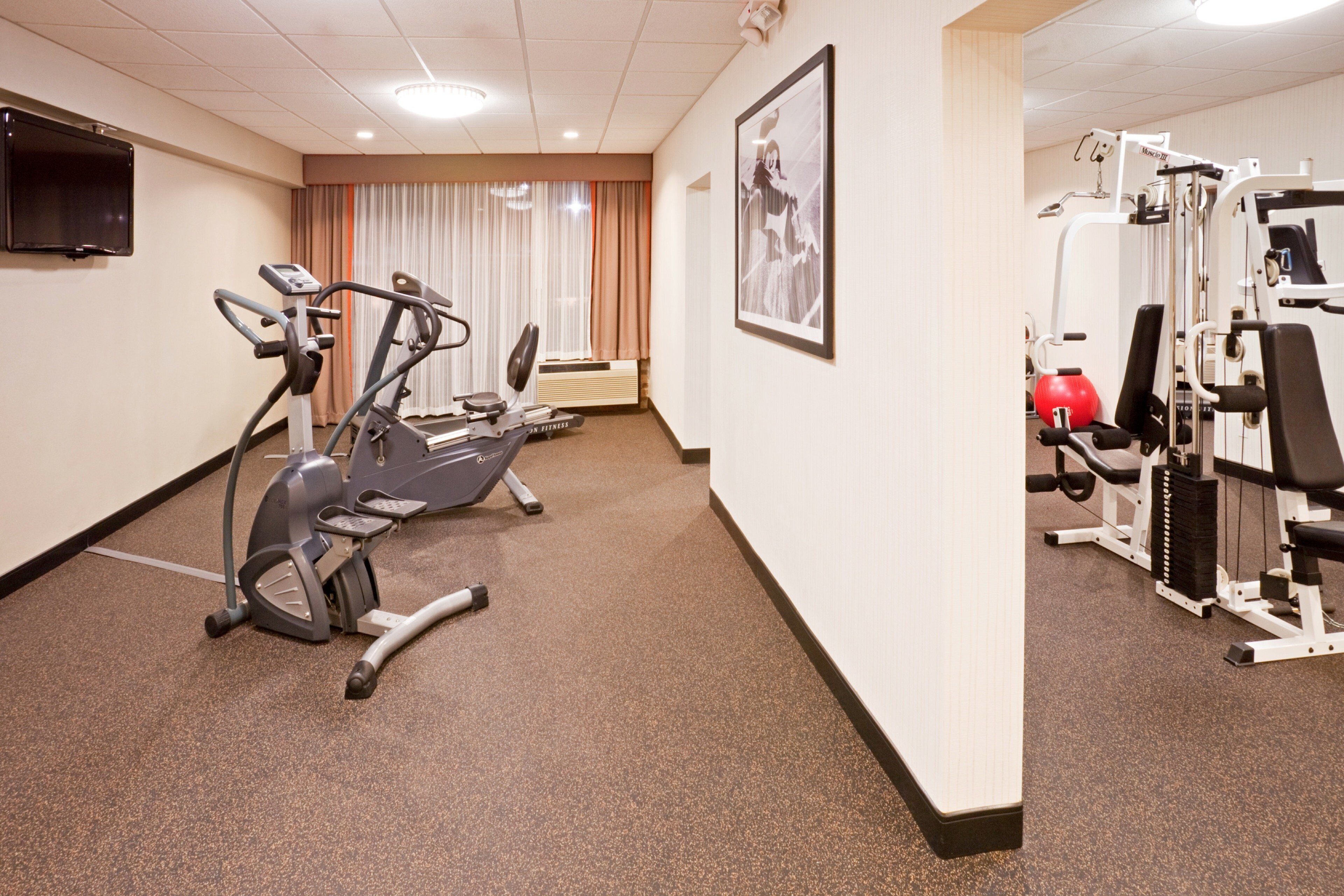 Un gimnasio con equipo de cardio, máquinas de pesas y una televisión.