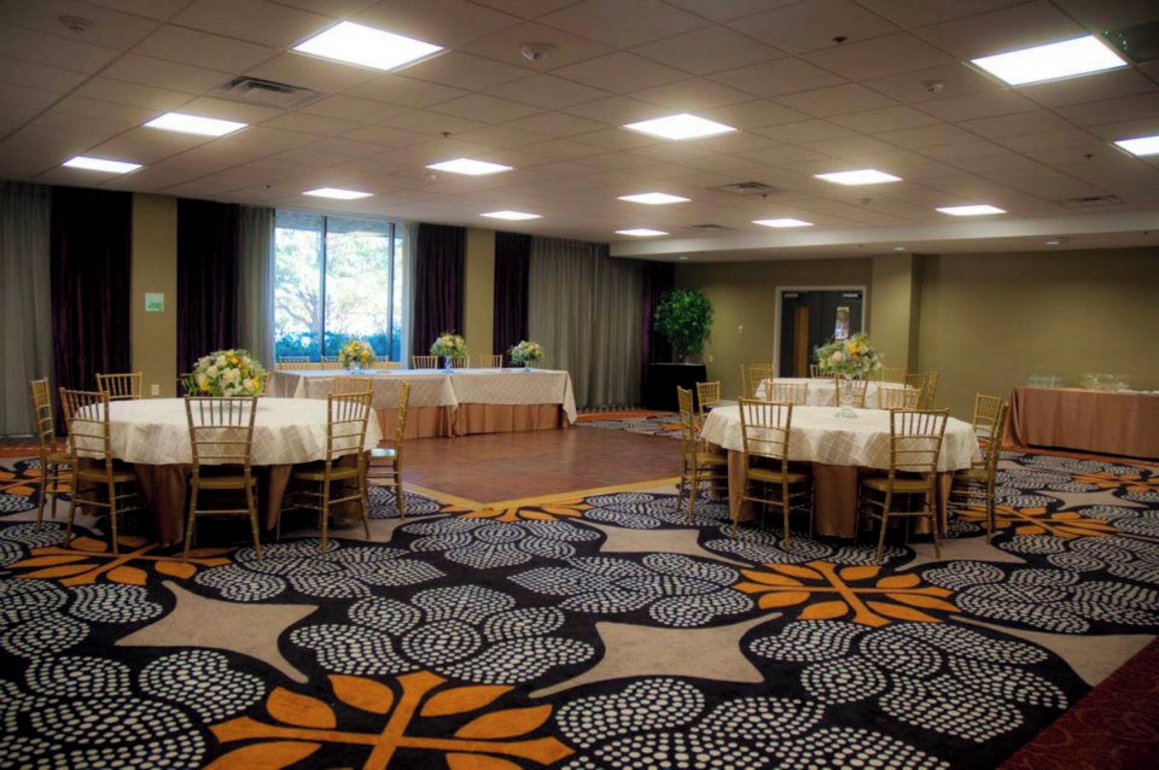 A conference room with tables and chairs, large windows, and a patterned carpet.