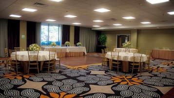 A conference room with tables and chairs, large windows, and a patterned carpet.