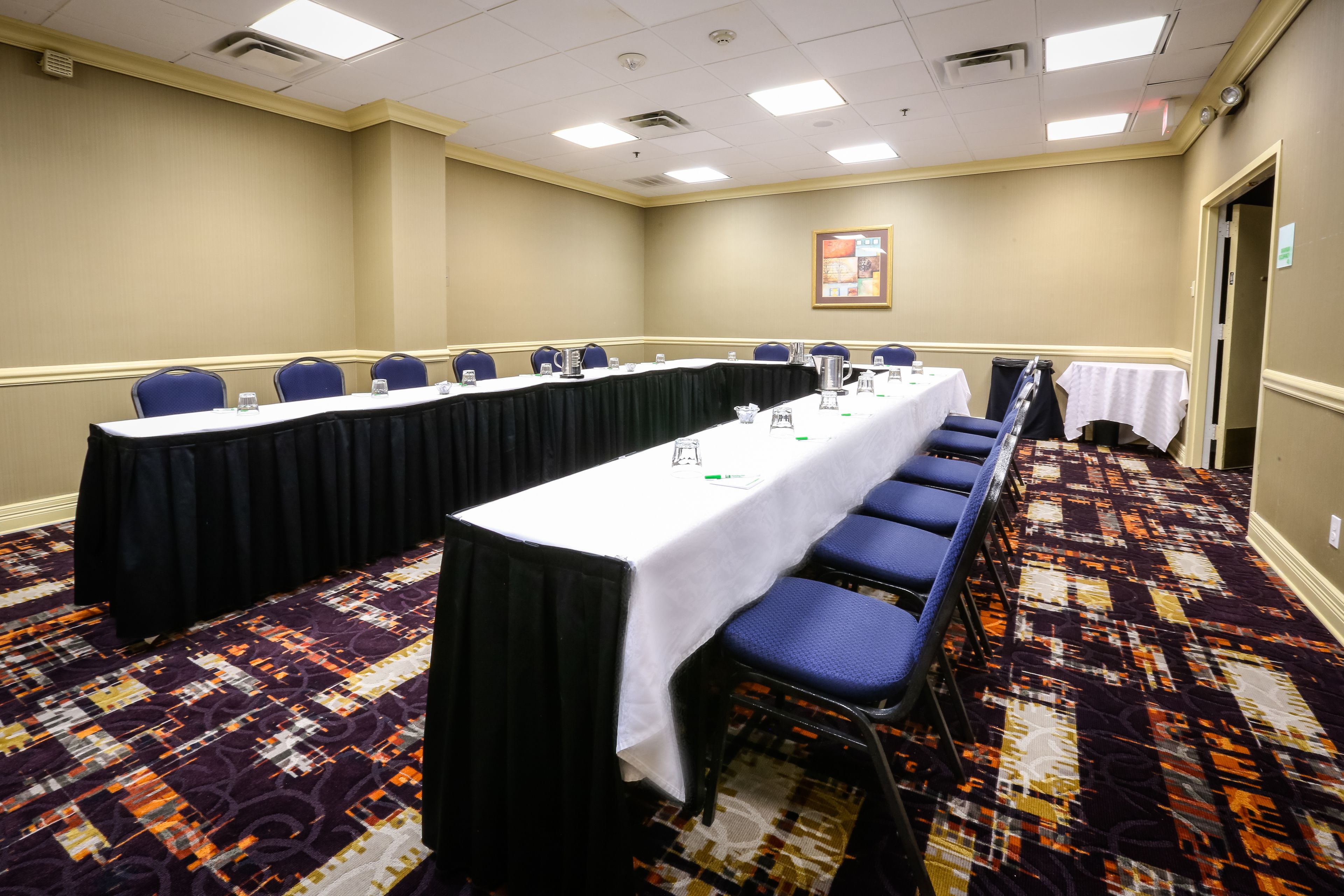 Un salón de conferencias con una larga mesa, sillas y suelo alfombrado.