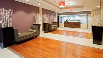 A reception area with a wooden floor, a reception desk, and seating with decorative vases.
