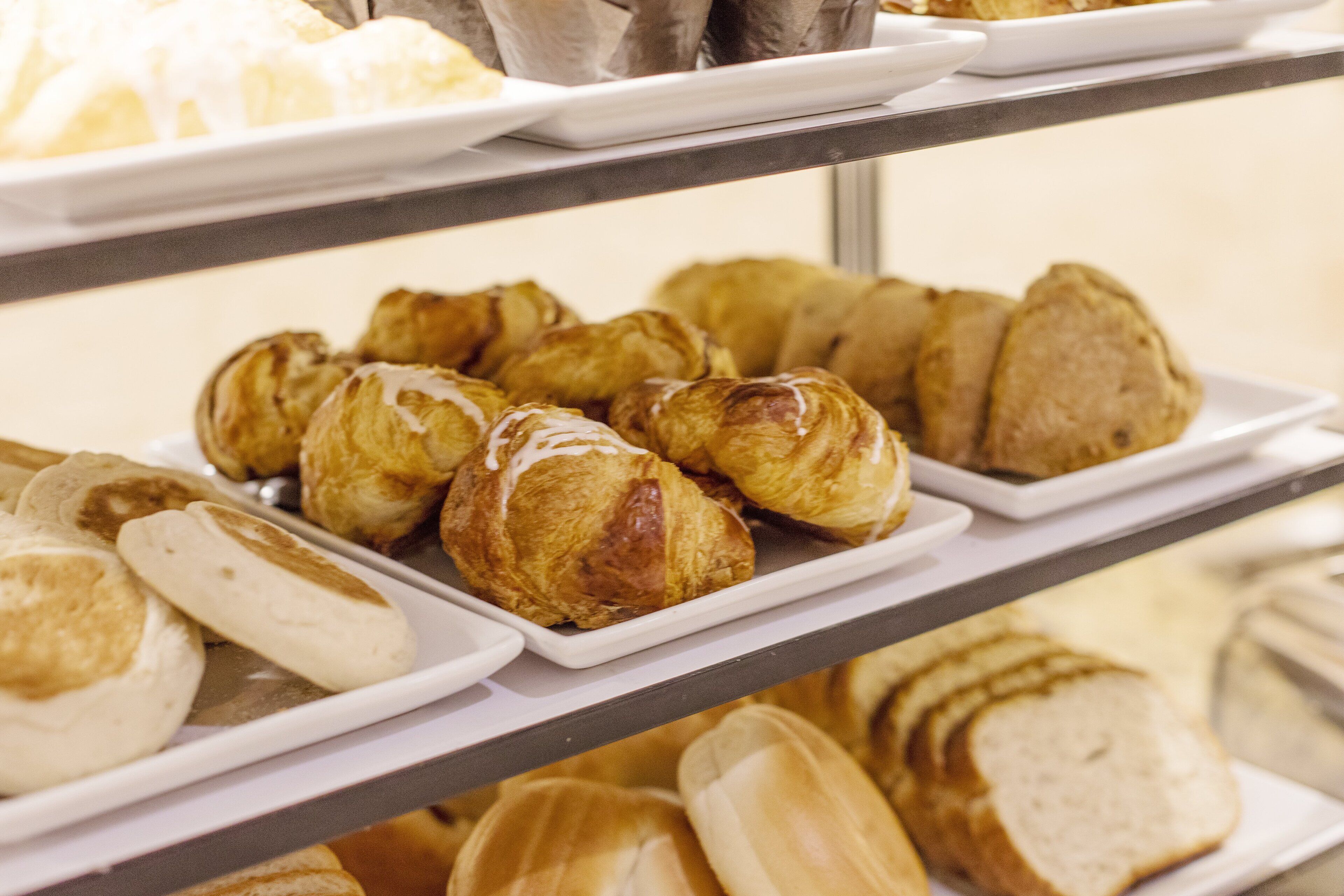 Una vitrina de panadería con diversos productos horneados, incluyendo pasteles y pan.