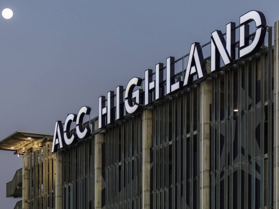 Un edificio con el cartel 'ACC HIGHLAND' iluminado contra el cielo nocturno.