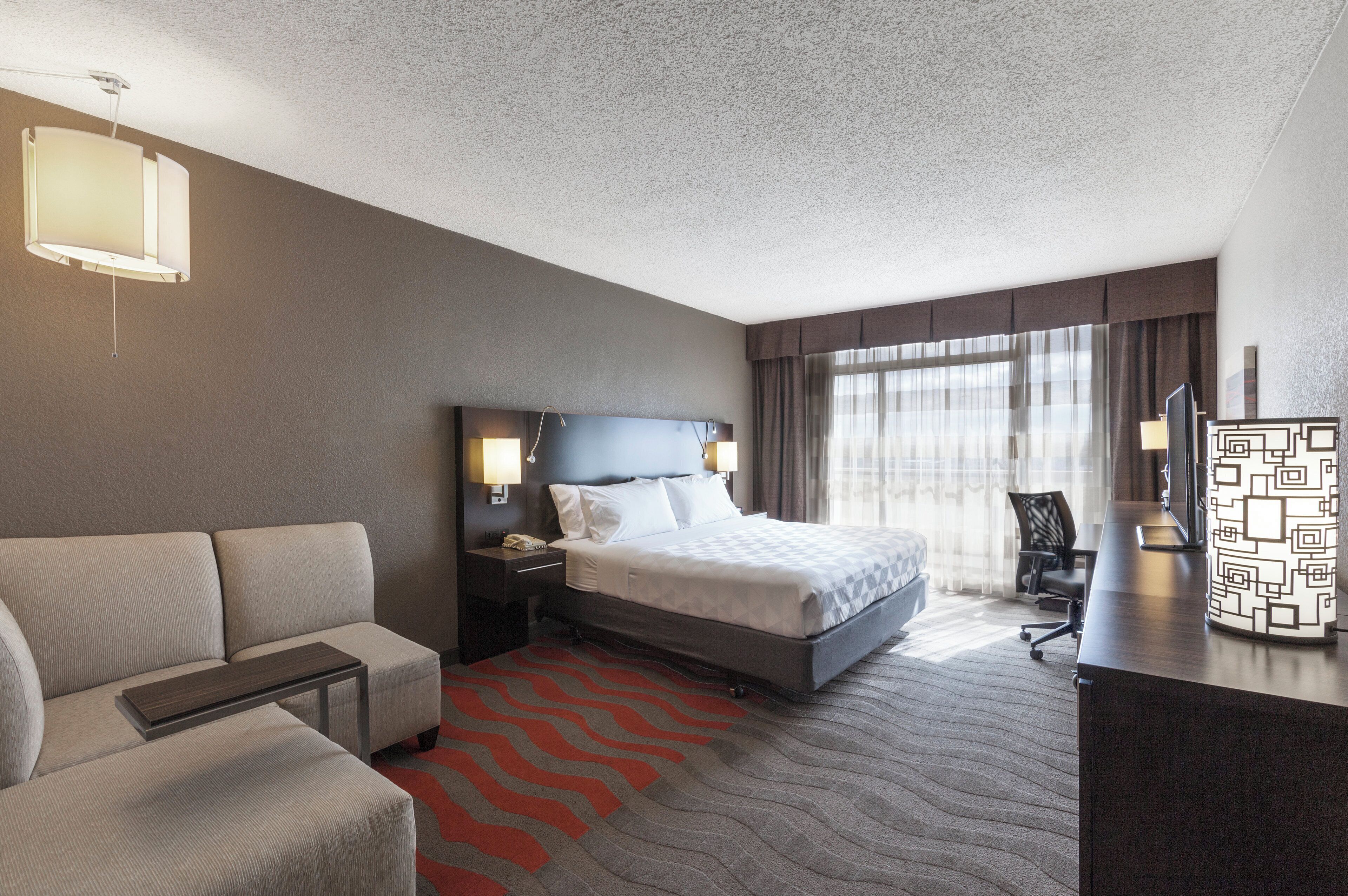 A hotel room with a bed, a sofa, a desk, and a chair.