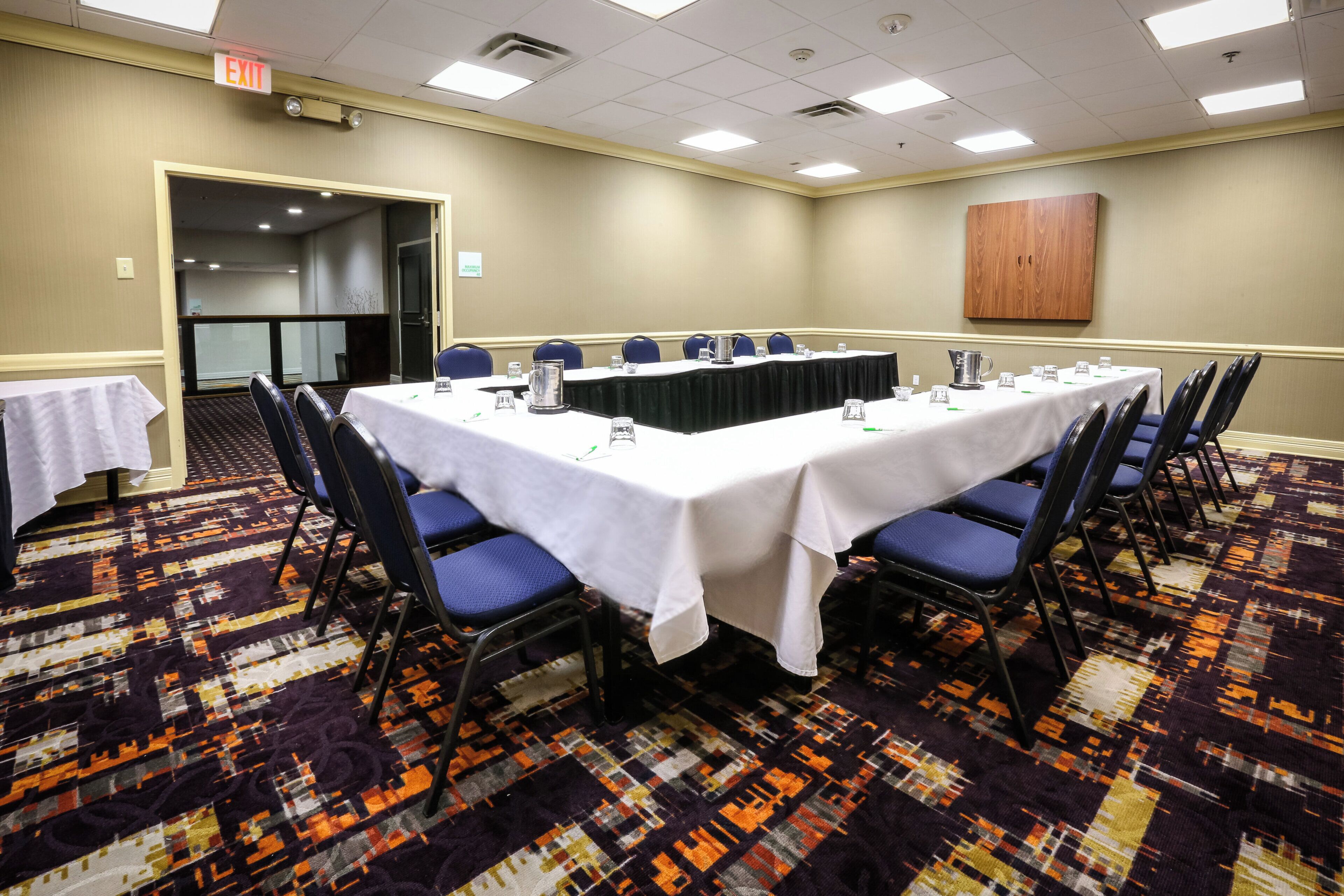 Un salón de conferencias con una mesa larga, sillas y piso alfombrado.