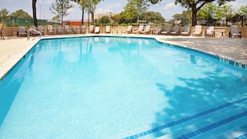 Una piscina cristalina con sillas de descanso y un solárium empinado.