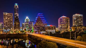 A city skyline with illuminated buildings and a bridge.