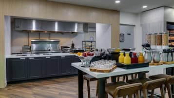 Une cuisine moderne équipée d’appareils électroménagers en acier inoxydable, agrémentée d’un panier de fruits et dotée d’un coin bar avec des tabourets.