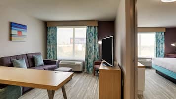 A hotel room with a sofa, a desk, a TV, and a bed.
