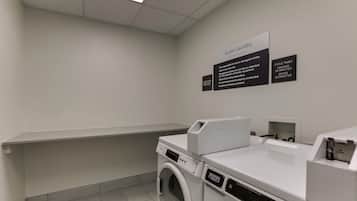 Un espace buanderie équipé d’un lave-linge, d’un sèche-linge et d’un panneau indiquant qu’il est réservé à l’usage des clients.