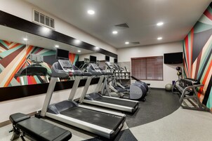 Un gimnasio con cintas de correr, elípticas y equipo de pesas.