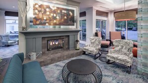 A modern lounge area with a fireplace, comfortable seating, and a large TV screen displaying a firefly-themed advertisement.