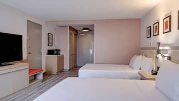 A hotel room with two beds, a TV, a desk, and a shower area.