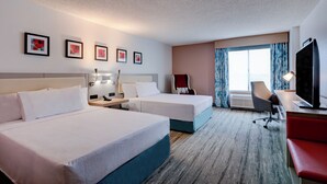 A hotel room with two beds, a desk with a chair, a TV, and a window with curtains. - Hilton Garden Inn Anaheim Garden Grove (Garden Grove)