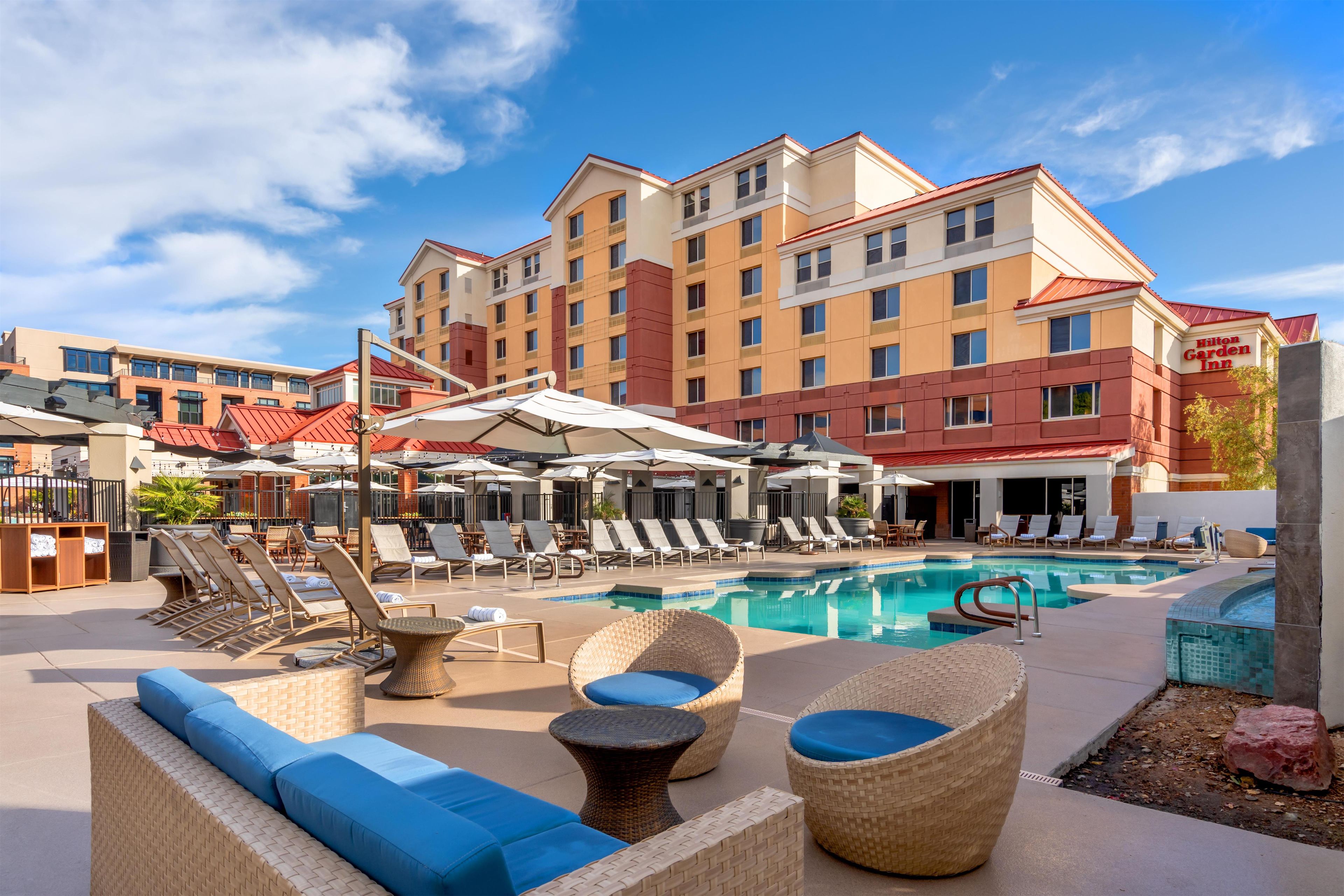 A hotel pool area with lounge chairs, umbrellas, and a swimming pool.