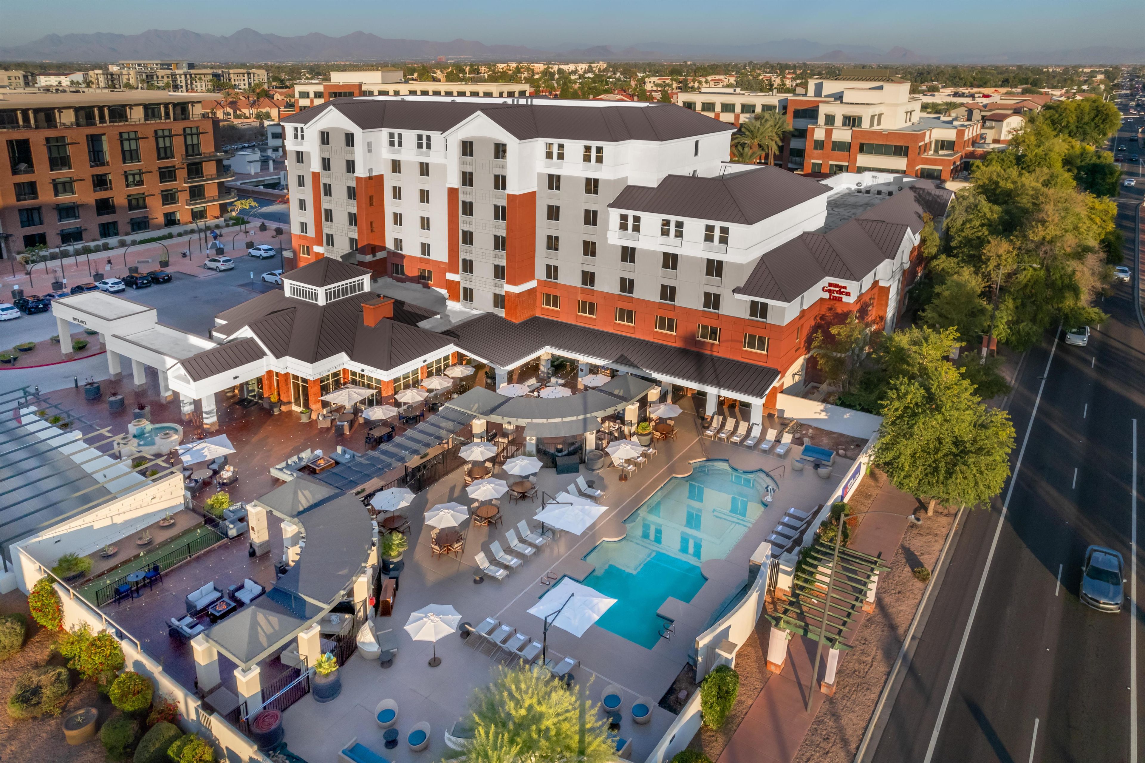 A hotel with a rooftop pool, outdoor seating, and a view of the surrounding cityscape.