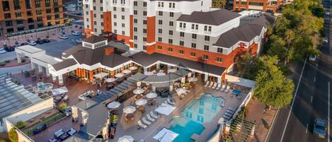 A hotel with a rooftop pool, outdoor seating, and a view of the surrounding cityscape.