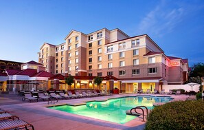 A hotel with a swimming pool, outdoor seating, and a well-lit facade. - Hilton Garden Inn Scottsdale Old Town (Scottsdale)