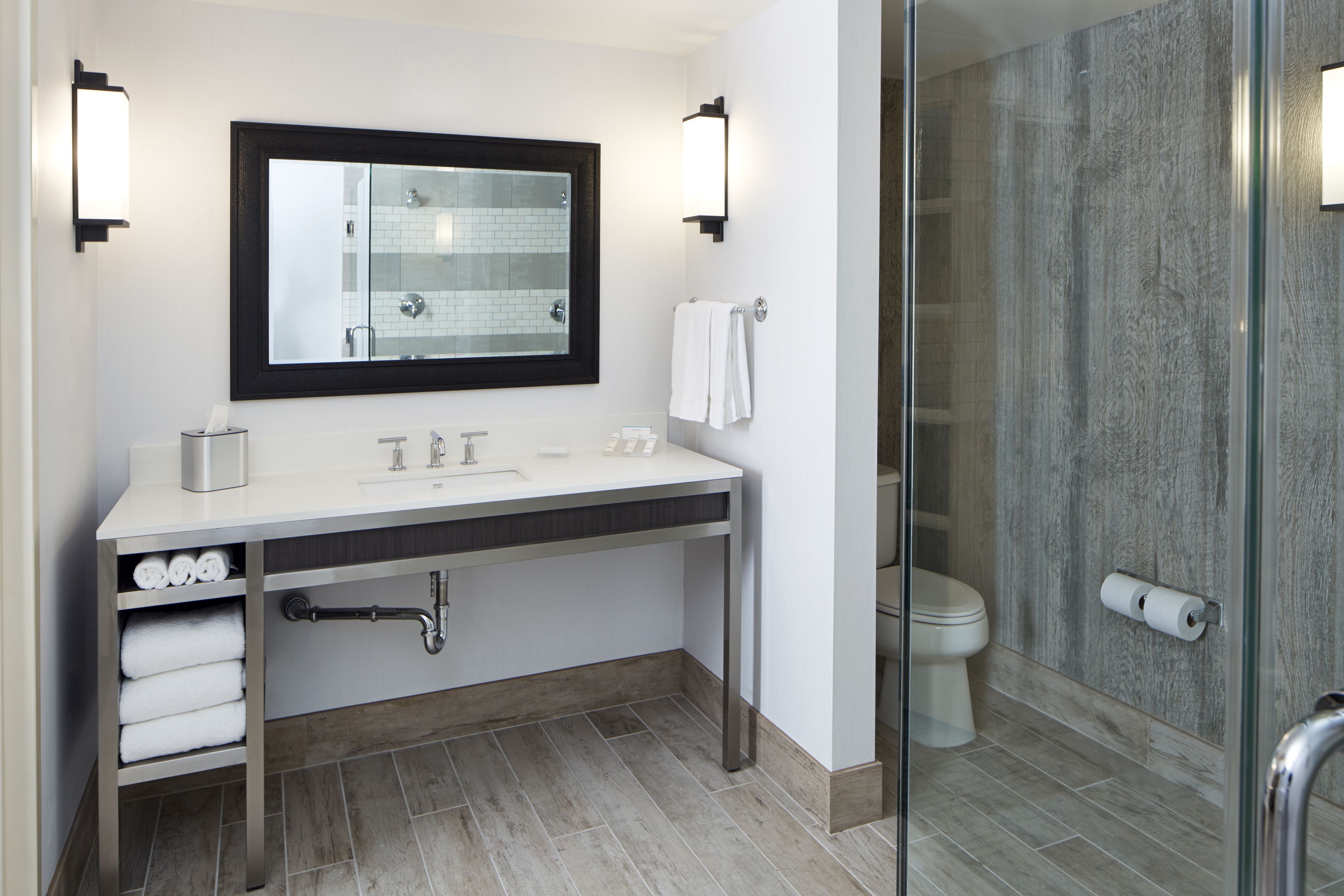 A modern bathroom with a white sink, a mirror with a black frame, and a glass shower enclosure.