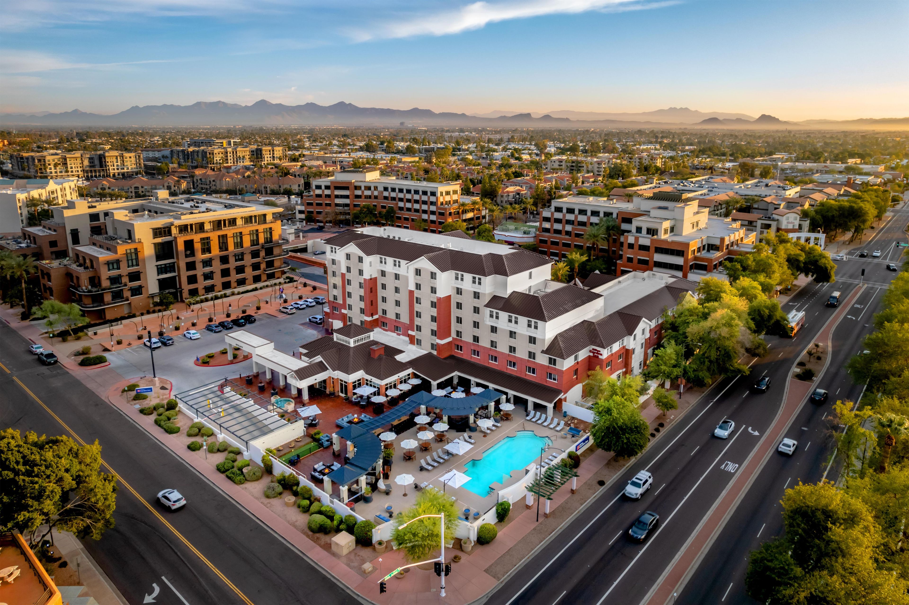 A hotel with a swimming pool, multiple floors, and a parking lot.