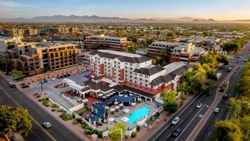 A hotel with a swimming pool, multiple floors, and a parking lot.