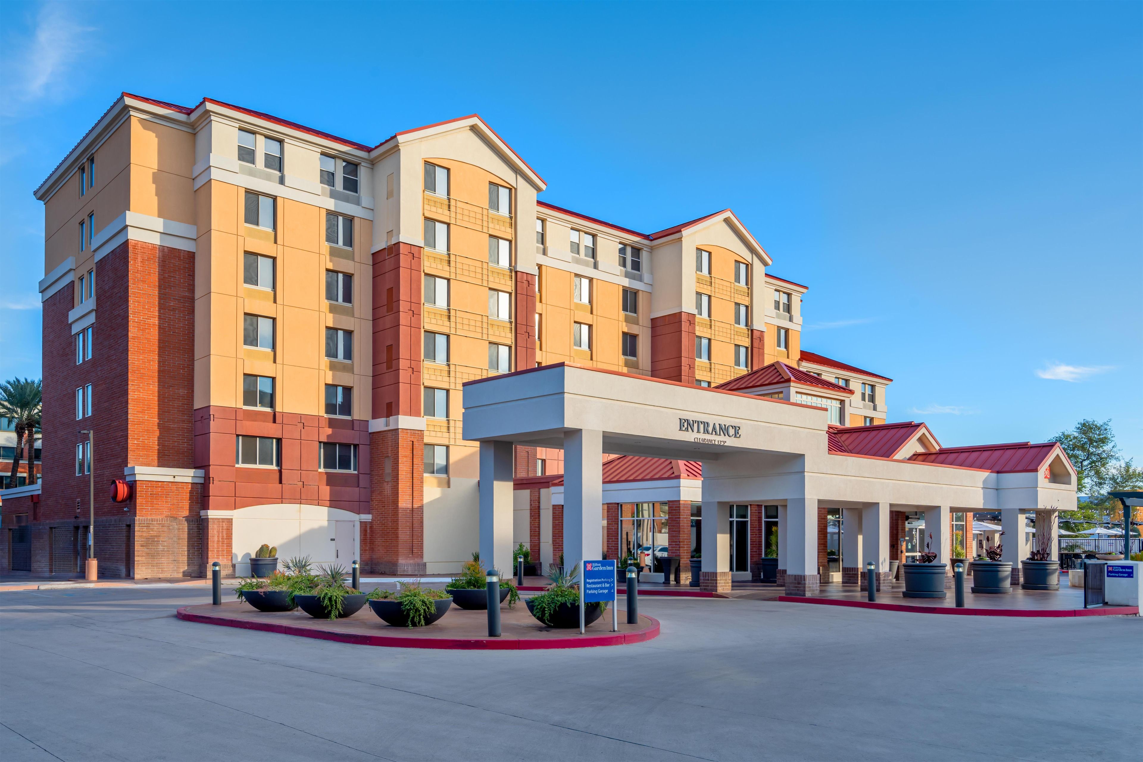 A multi-story hotel with a clear entrance, a sign indicating the name, and directional signs for amenities.