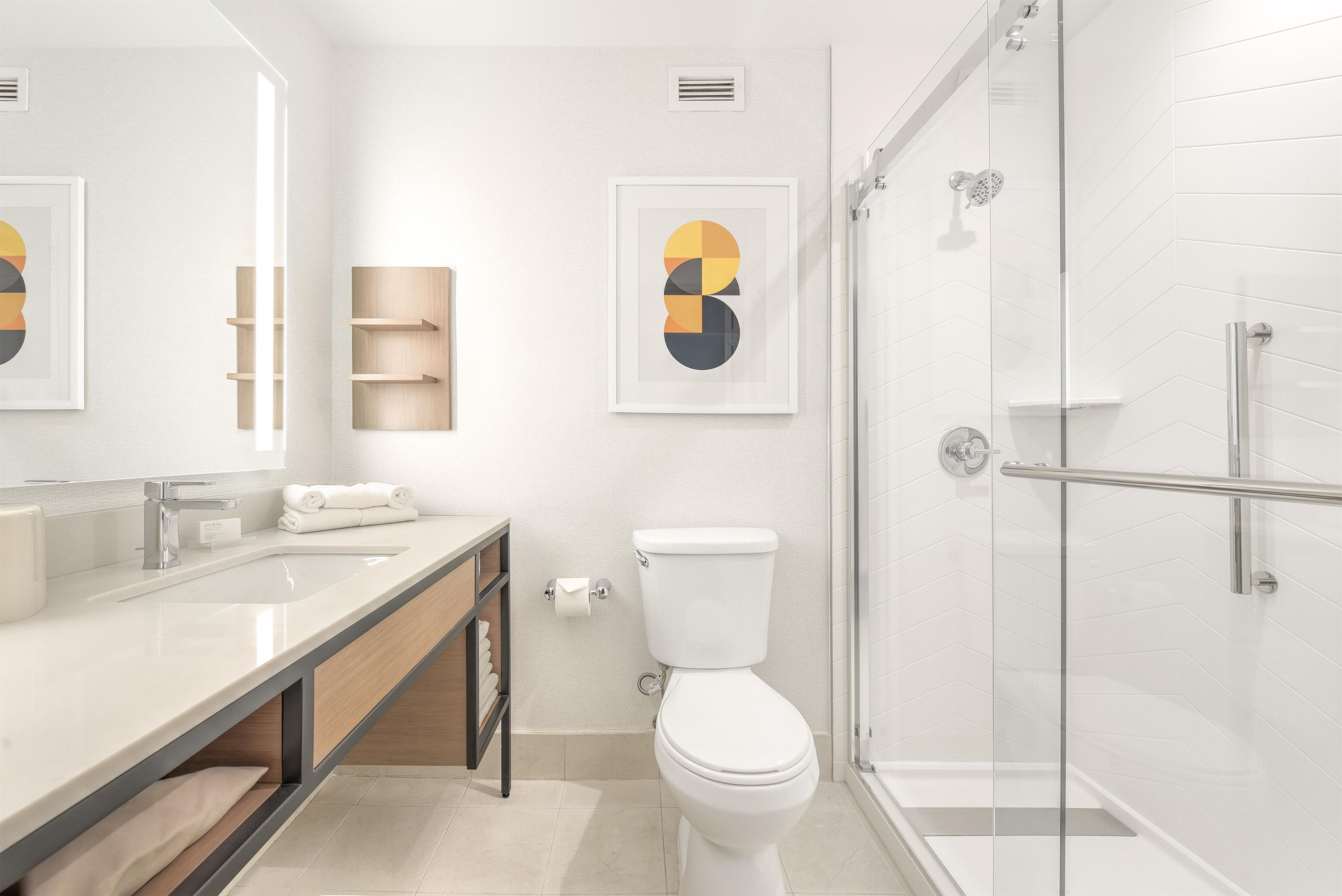 A modern bathroom with a glass shower enclosure, a toilet, and a sink with a mirror.