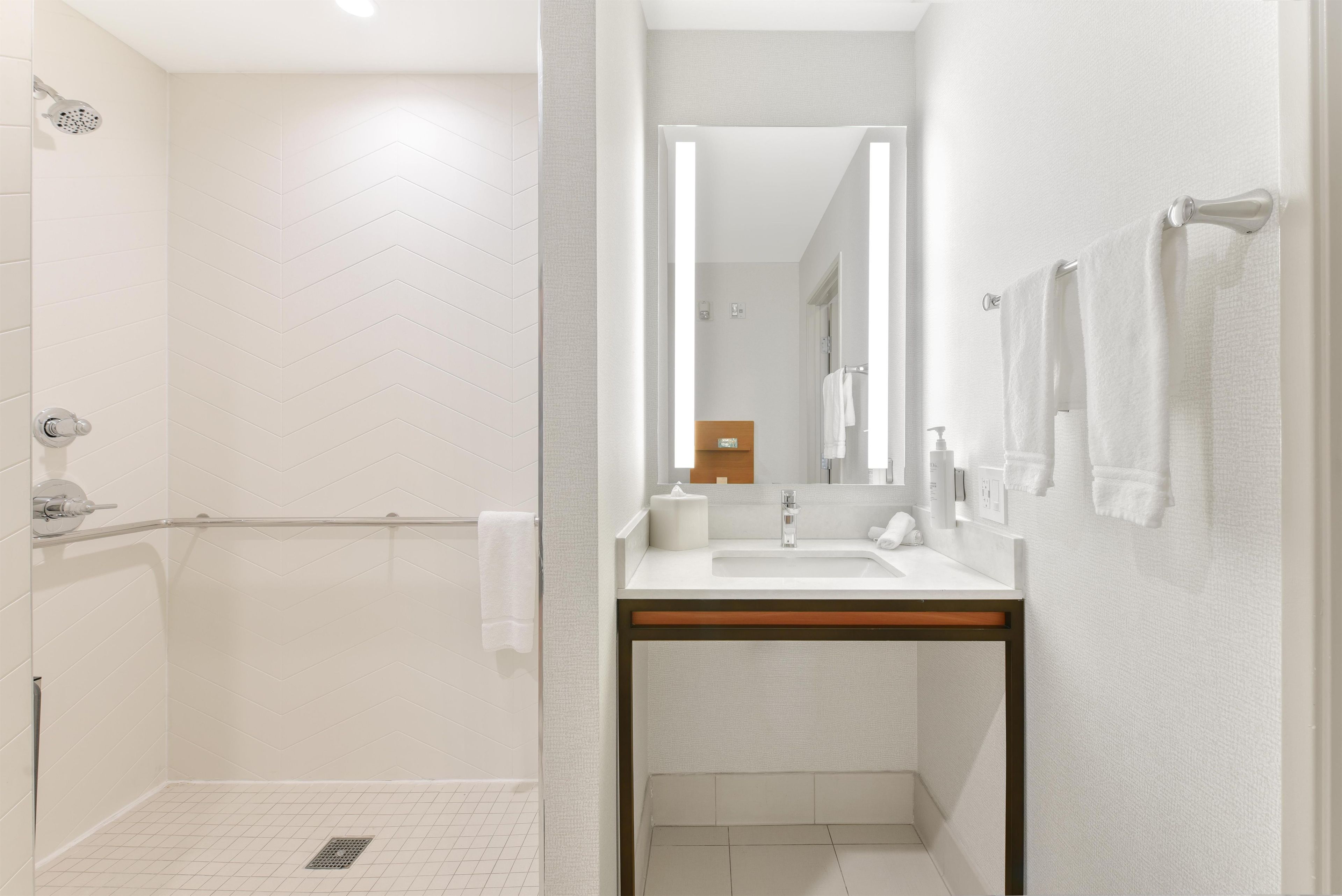 A modern bathroom with a shower, toilet, and sink.
