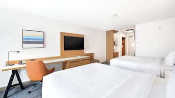 A hotel room with a bed, a desk, a chair, a television, and a framed picture on the wall.