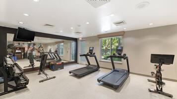 A gym with treadmills, a rowing machine, and a weight bench.