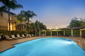 Una piscina al aire libre, sillones reclinables de piscina