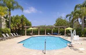 A swimming pool with lounge chairs and umbrellas, surrounded by palm trees and a pergola. - Hilton Garden Inn LAX El Segundo (El Segundo)