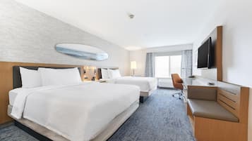 A hotel room with two beds, a desk, a chair, and a television.