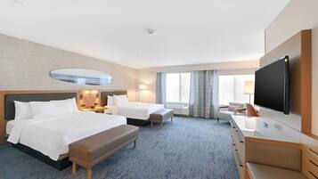A hotel room with two beds, a desk, a flat-screen TV, and a large window.
