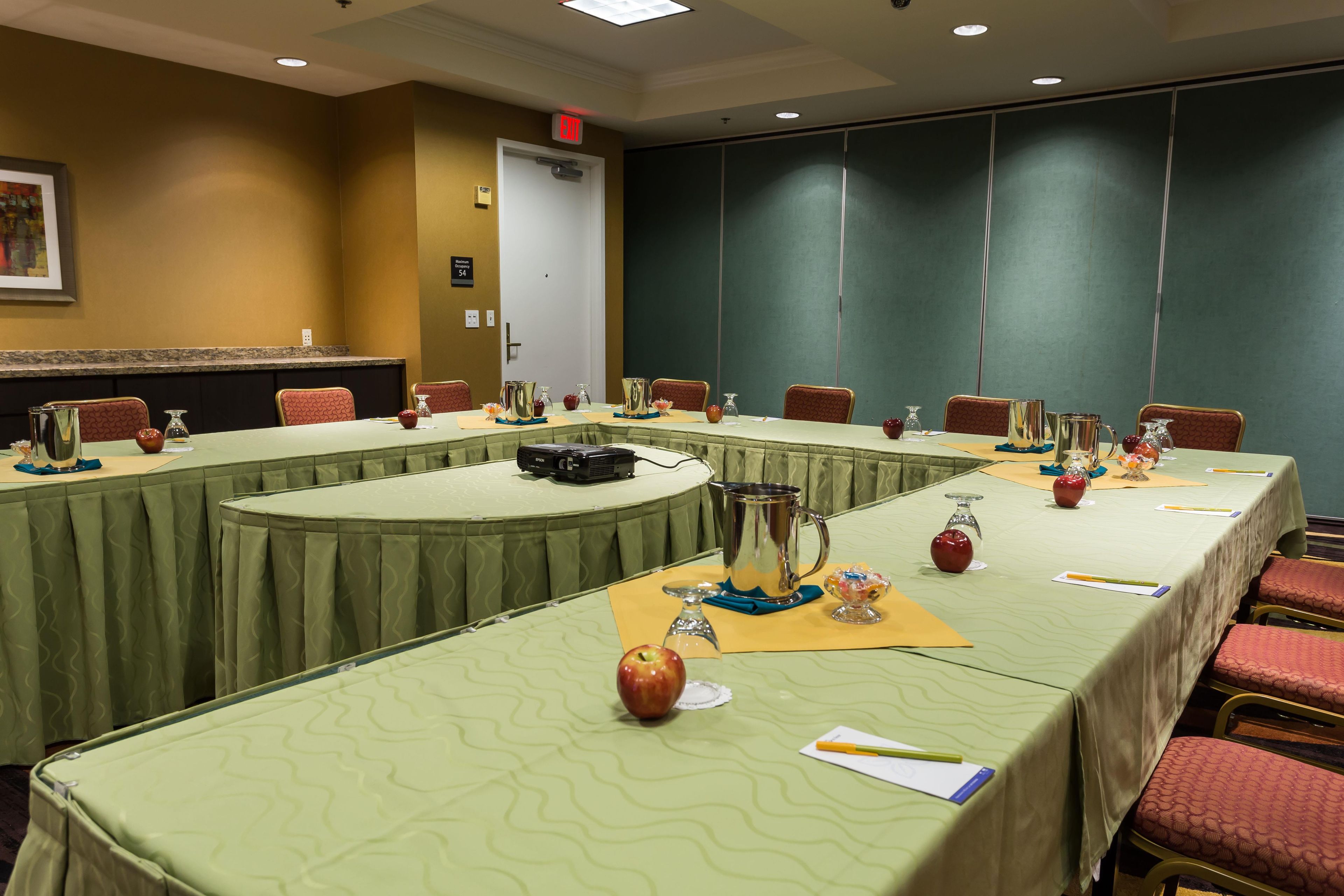 A conference room with a long table, chairs, and a projector.