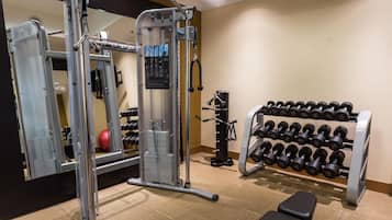 Une salle de sport équipée de matériel de musculation, d’un banc et d’un porte-haltères.